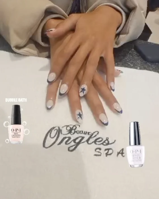 Mains aux ongles french bleu nuit et motif étoile, posées sur la serviette du salon