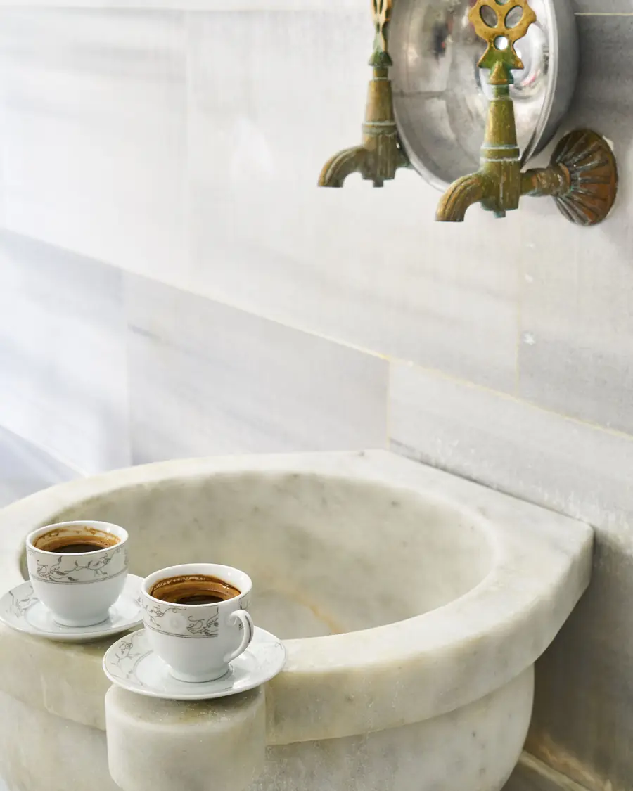 Vasque en marbre du hammam et deux tasses de café posées sur le rebord