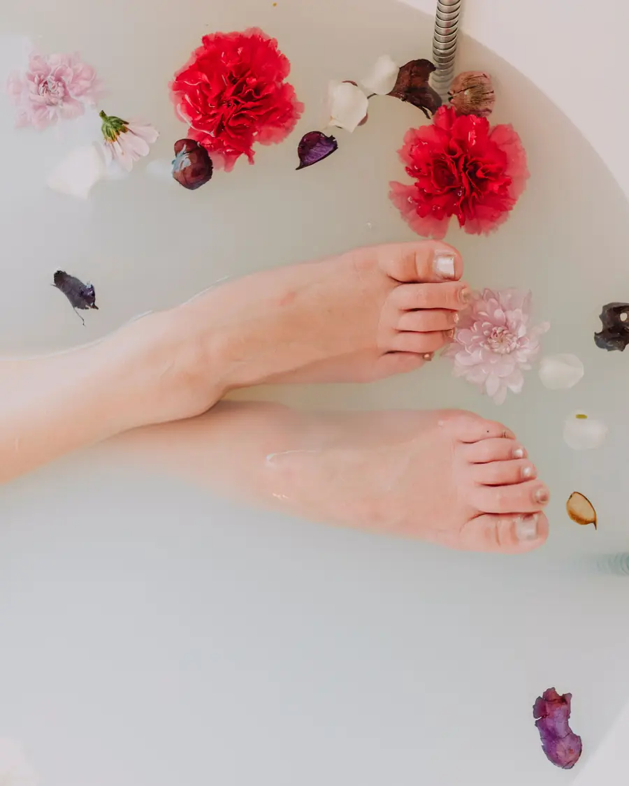 Pieds dans un bain de lait parsemé de fleurs roses et rouges