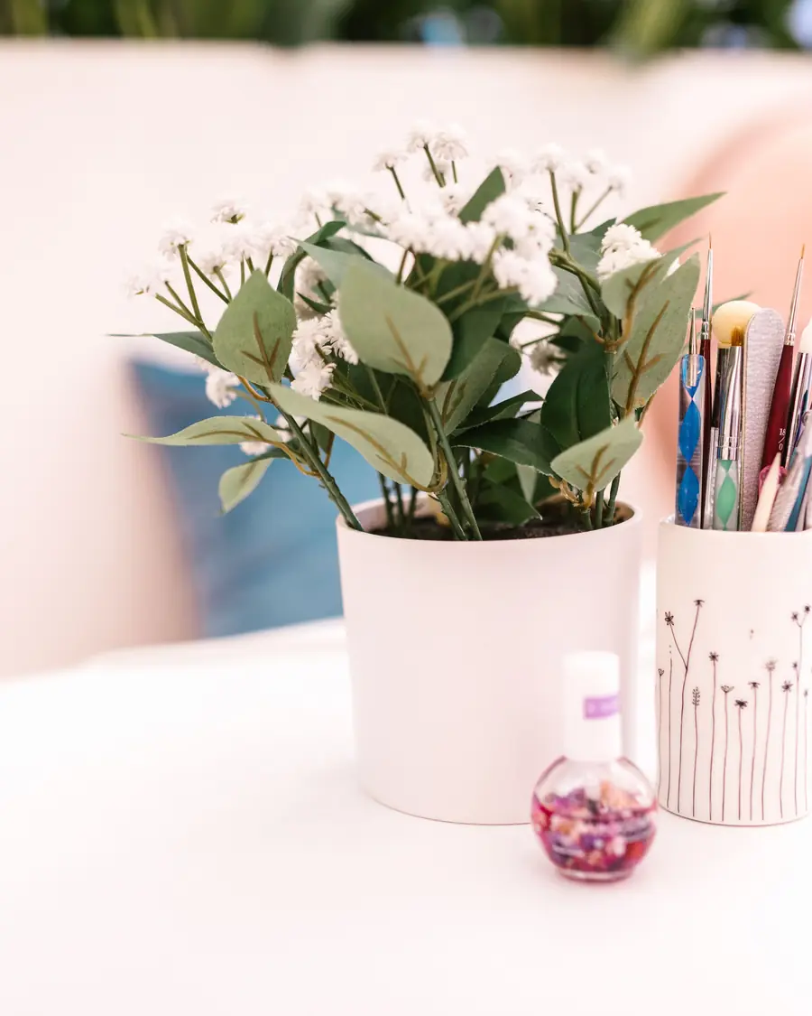Coin de travail du salon, pinceaux à ongles et soin des cuticules sur un plan blanc
